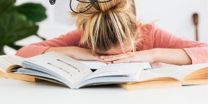 Woman with her head on the desk because she needs to overcome limiting beliefs